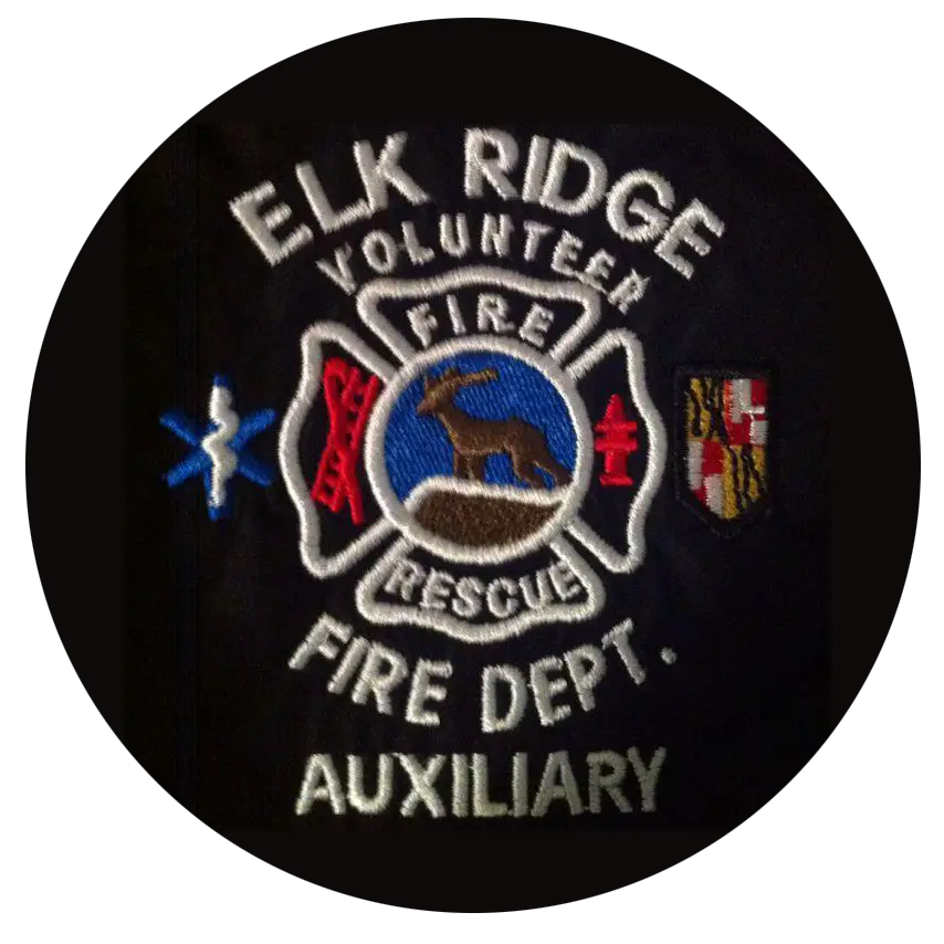 A circular embroidered patch for the Elk Ridge Volunteer Fire Department Auxiliary. It features symbols related to firefighting and EMS, along with a central emblem depicting a deer. The words "Fire Rescue" are prominently displayed in the center.